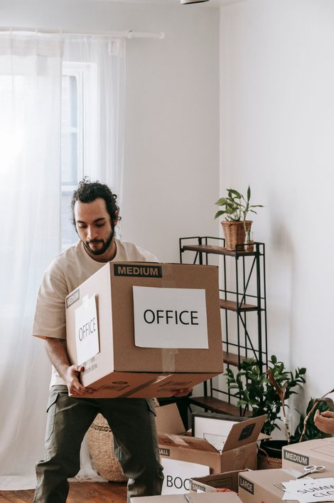 A worker carrying a labeled office moving box